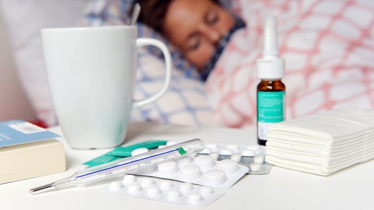 Eine Frau liegt mit einer Grippe-Erkrankung im Bett.