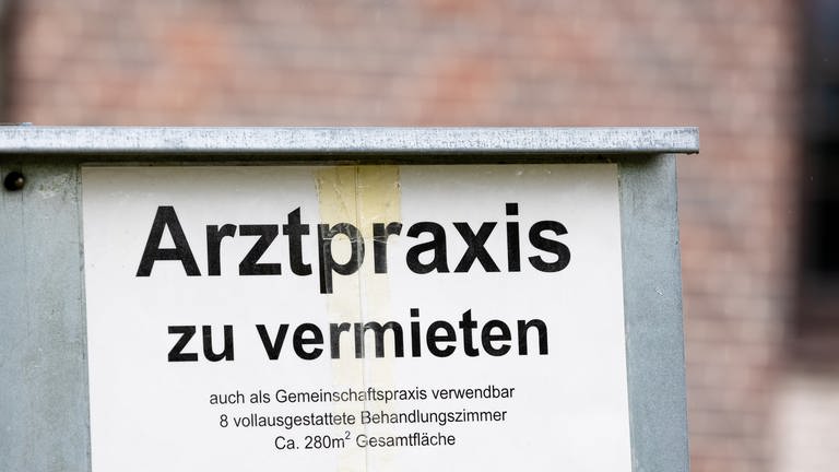 Ein Schild mit der Aufschrift "Arztpraxis zu vermieten" steht vor einem Gebäude. (Foto: dpa Bildfunk, picture alliance/dpa | Moritz Frankenberg)