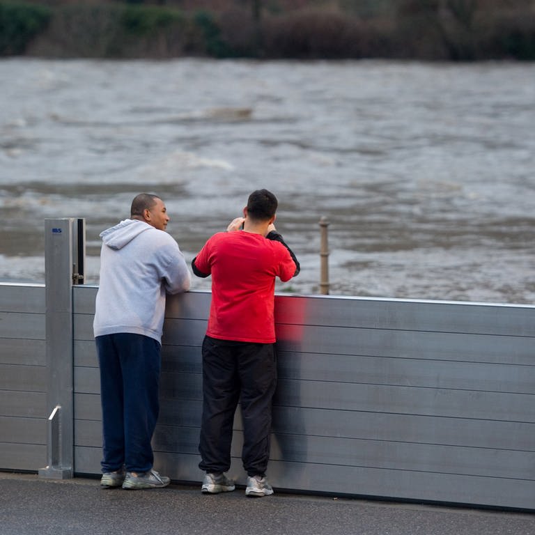 Zwei Schaulustige stehen an den Spundwänden, zum Schutz gegen das Hochwasser aufgebaut wurden.  (Foto: dpa Bildfunk, Picture Alliance)