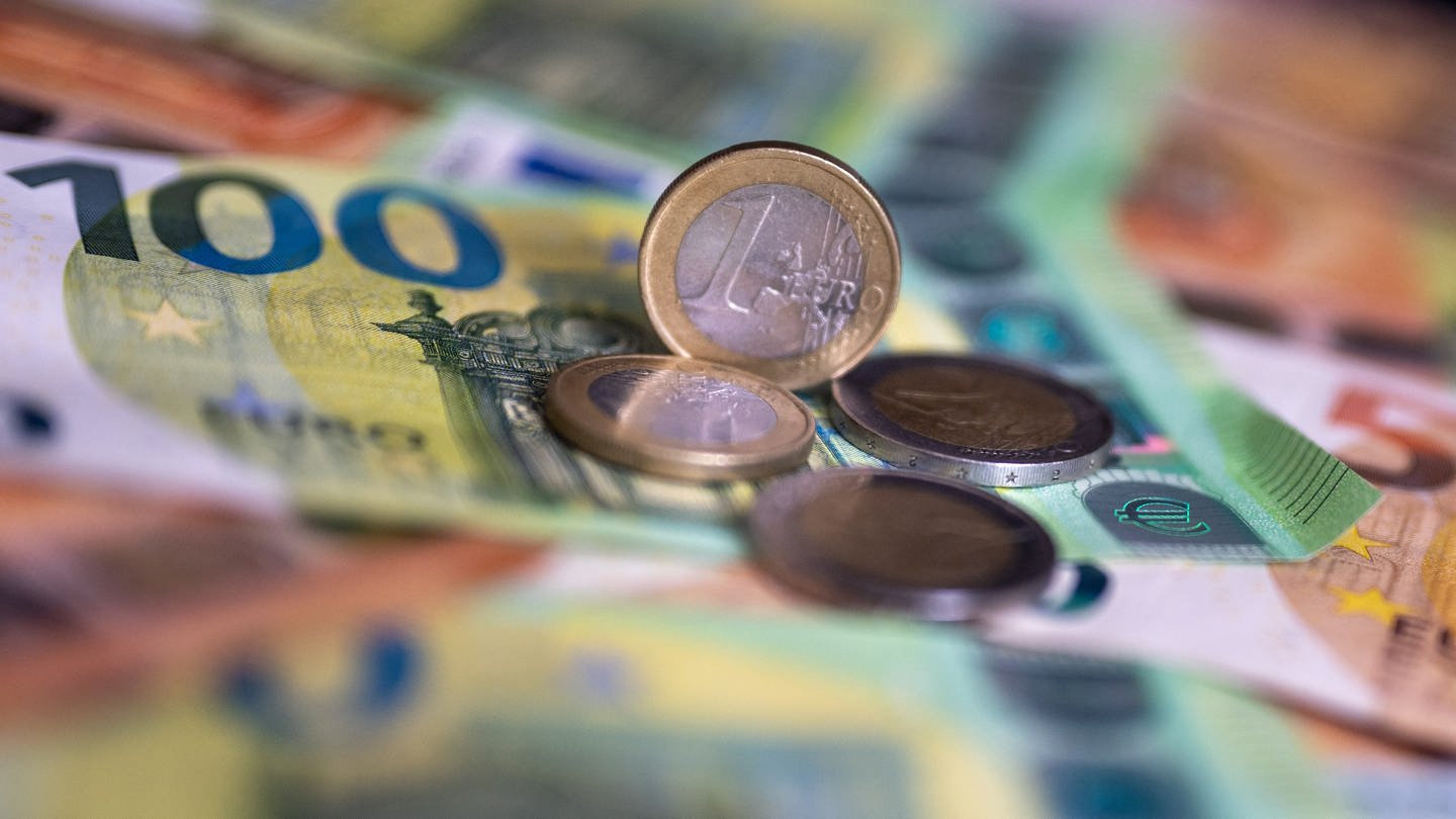 Geldscheine mit dem Wert von 100 und 50 Euro und Münzen liegen auf einem Tisch. Viele Versicherungen 2024 werden teurer. (Foto: dpa Bildfunk, picture alliance/dpa | Monika Skolimowska)