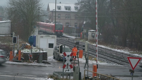 Am Bahnübergang in Grünsfeld (Main-Tauber-Kreis) steht ein Bahnmitarbeiter an der offenen Schranke. (Foto: SWR)