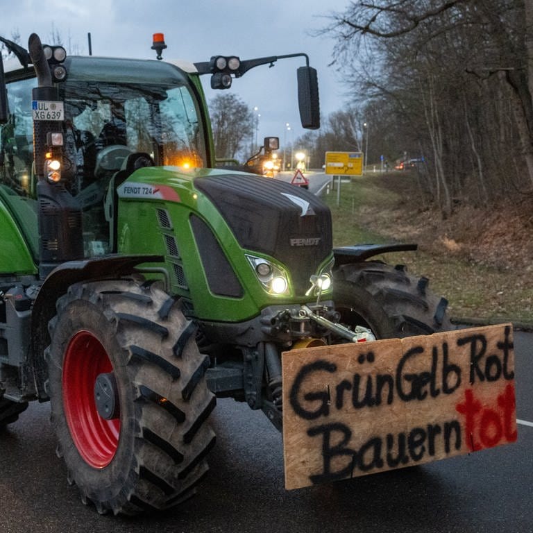 Landwirte fahren im Konvoi durch die Stadt, auf einem Plakat steht "GrünGelbRot Bauern tot". (Foto: dpa Bildfunk, picture alliance/dpa | Stefan Puchner)