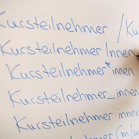 An einem Whiteboard steht das Wort Kursteilnehmer in verschiedenen Gender-Schreibweisen. (Foto: dpa Bildfunk, picture alliance/dpa | Uli Deck)