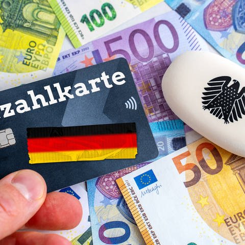  Ein Mann hält eine EC-Karte mit Aufschrift Bezahlkarte vor Euro Geldscheine. Die Bezahlkarte soll Deutschlandweit an Asylbewerber ausgegeben werden  (Foto: IMAGO, IMAGO / Bihlmayerfotografie)