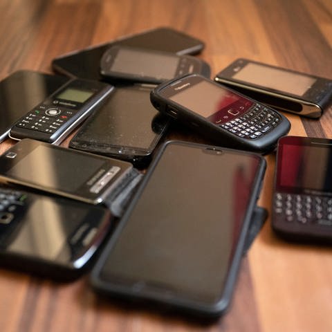Alte Handys und Smartphones liegen auf einem Tisch. Schätzungsweise rund 210 Millionen Altgeräte werden in Schubladen und Schränken in Deutschland gehortet. (Foto: dpa Bildfunk, picture alliance/dpa | Lisa Ducret)