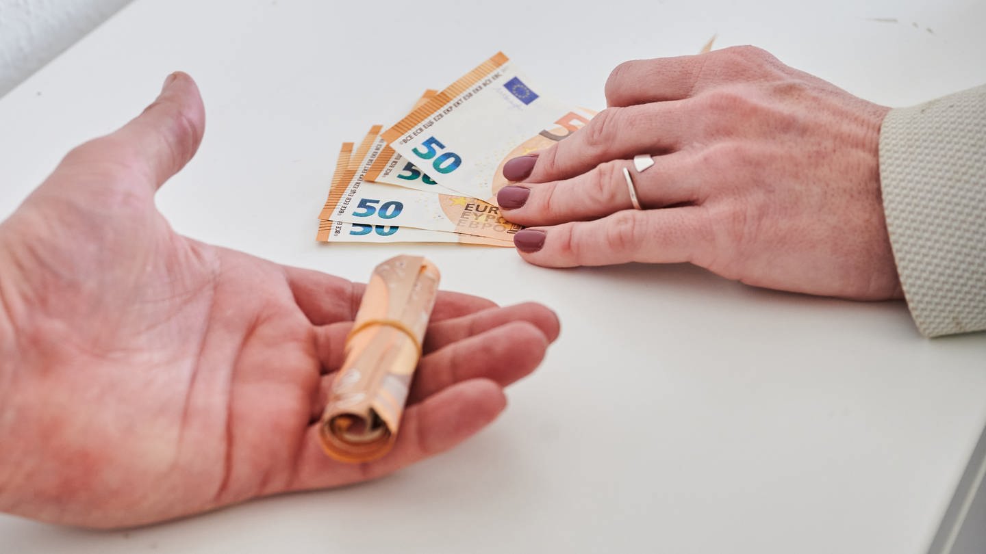 Eine Männerhand (l) hält ein Bündel 50-Euro-Scheine, während eine Frauenhand weniger 50-Euro-Scheine hält. (Foto: dpa Bildfunk, picture alliance/dpa | Annette Riedl)