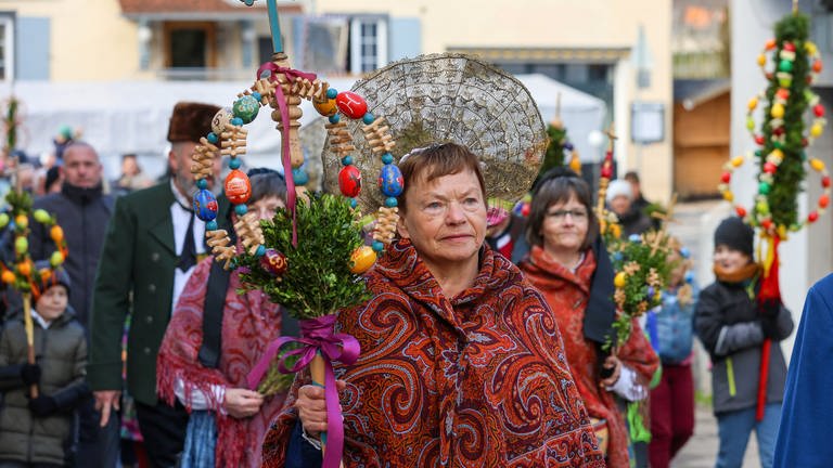 Frauen und Männer der Trachtengilde tragen an Palmsonntag während der Palmprozession einen "Palmen" durch die Straßen der Riedlinger Altstadt.  (Foto: dpa Bildfunk, picture alliance/dpa | Thomas Warnack)