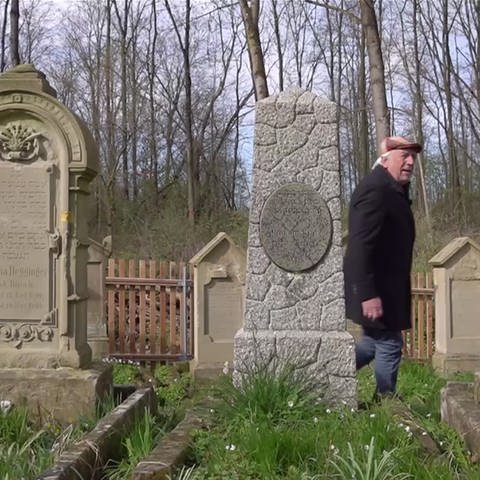Mann läuft zwischen Grabsteinen auf einem jüdischen Friedhof