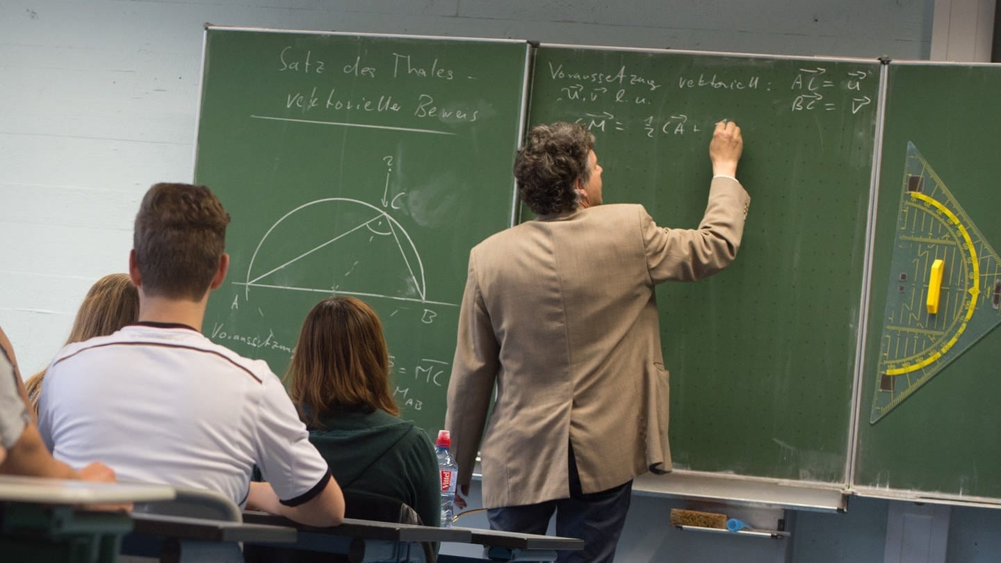 Ein Lehrer schreibt während des Matheunterrichts einer Abiturklasse an die Tafel. (Foto: dpa Bildfunk, picture alliance/dpa | Marijan Murat)