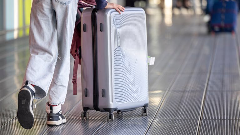 Frau schiebt Koffer am Flughafen