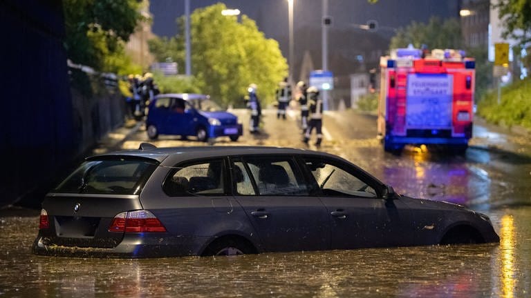 Ein Auto steht in Stuttgart in einer überfluteten Autounterführung. 