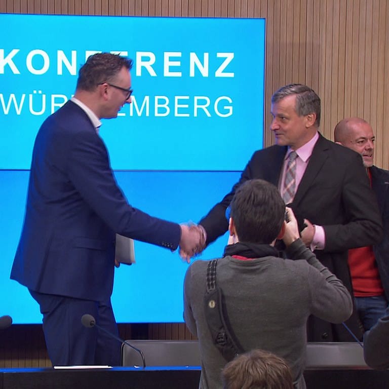 Die Fraktionsvorsitzenden im Landtag von Baden-Württemberg, Andreas Schwarz (Grüne) und Hans-Ulrich Rülke (FDP), schütteln sich auf der Landespressekonferenz in Stuttgart die Hand. (Foto: SWR)