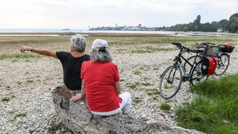 Zwei Seniorinnen sitzen nach einer Radtour vor Friedrichshafen am Ufer des Bodensees. (Foto: dpa Bildfunk, picture alliance/dpa | Felix Kästle)