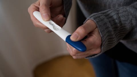  Eine Frau hält einen negativen Schwangerschaftstest in der Hand (Foto: dpa Bildfunk, picture alliance / dpa Themendienst | Christin Klose)