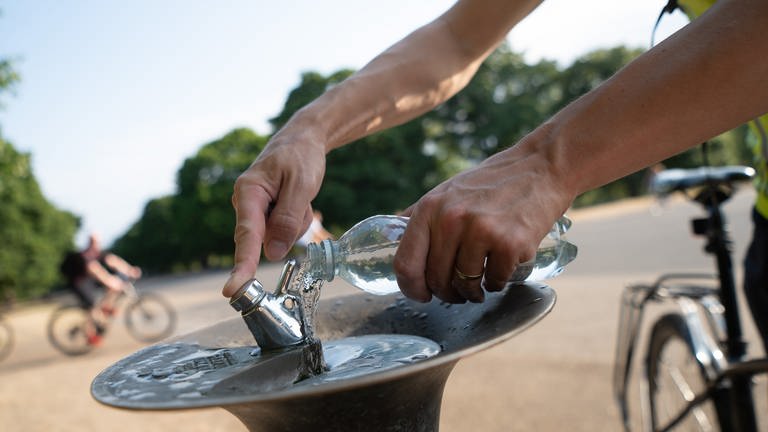 Ein Mann füllt im Park Kensington Gardens an einem Trinkbrunnen seine Wasserflasche auf.  (Foto: dpa Bildfunk, picture alliance/dpa | Sebastian Gollnow)