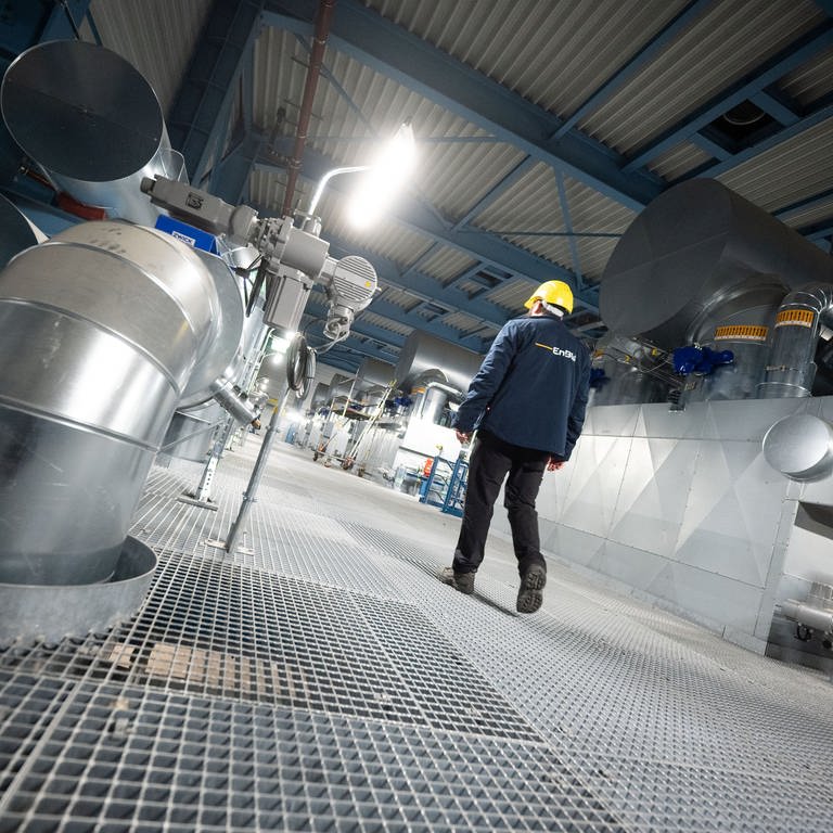 Ein Mitarbeiter des Energiekonzerns EnBW geht an Anlagen des Heizkraftwerk 3 Stuttgart-Gaisburg vorbei, rechts ist ein Gaskessel zur Warmwasserbereitung zu sehen.