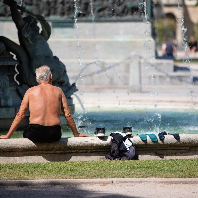Ein Mann kühlt sich bei heißen Temperaturen an einem Brunnen in der Stuttgarter Innenstadt ab.