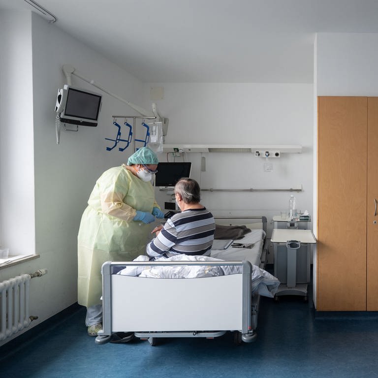Eine Krankenpflegerin betreut in einem Patientenzimmer einer Covid-19-Station im Klinikum Stuttgart einen Patienten. (Foto: dpa Bildfunk, picture alliance/dpa | Marijan Murat)