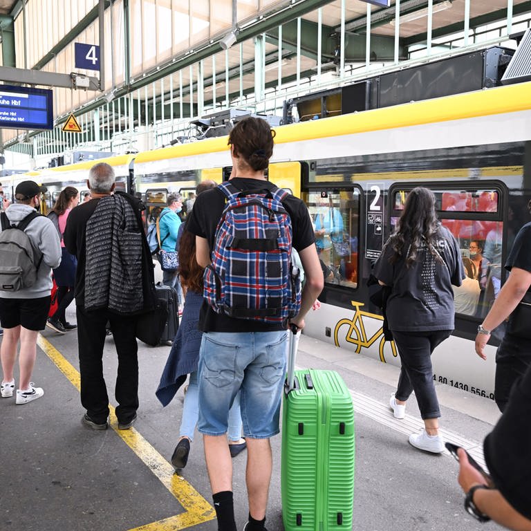 Menschen gehen auf einem Bahnsteig auf dem Hauptbahnhof Stuttgart zu ihrem Zug. (Foto: dpa Bildfunk, picture alliance/dpa | Bernd Weißbrod)