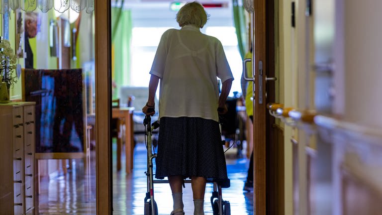 Eine Pflegeheimbewohnerin läuft mit Rollator über den Flur ihrer Einrichtung, die immer teurer wird.