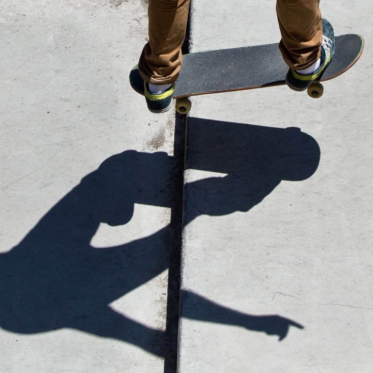 Skateboard und Beine eines Jugendlichen im Skatepark inklusive Schatten. (Foto: dpa Bildfunk, picture alliance / dpa | Daniel Karmann)