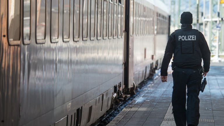 Ein Bundespolizist geht am Bahnhof in Passau neben einem Zug. Grenzkontrollen wegen der Flüchtlinge aus der Ukraine sorgen zum Teil für Verspätungen.