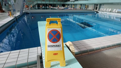 Ein "Gesperrt"-Schld steht vor einem Schwimmbecken mit Wasser, aber ohne Schwimmer (Foto: dpa Bildfunk, Oliver Berg)