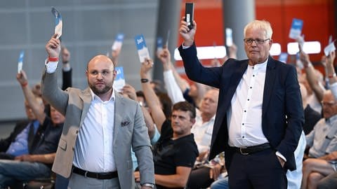 Die AfD Politiker Markus Frohnmaier (l) und Emil Sänze stehen in der Messehalle in Stuttgart beim AfD Landesparteitag gemeinsam im Saal. Sie werden zur neuen Doppelspitze im Land gewählt.