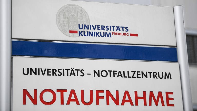 Ein Schild mit der Aufschrift "Universitätsklinikum Freiburg und Notaufnahme" steht vor einem Gebäude. (Foto: dpa Bildfunk, picture alliance/dpa | Patrick Seeger)