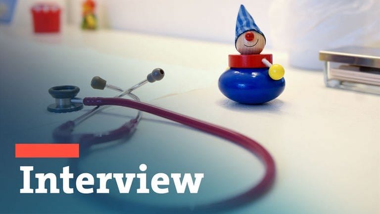 Ein Stethoskop und Kinderspielzeug liegen in einer Kinderarztpraxis auf einem Tisch.