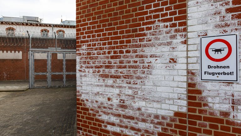 Gefängnismauern der Justizvollzugsanstalt Neumünster mit Hinweisschild für Drohnenflugverbot. (Foto: IMAGO, Imago / Olaf Döring)