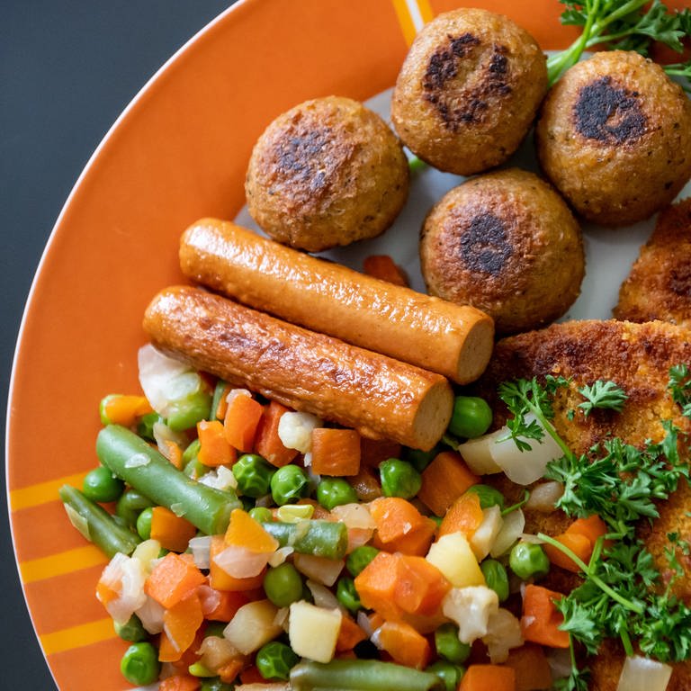 Vegane Falafel, vegane Schnitzel, vegane Würstchen und Gemüse sind auf einem Teller in einer Küche zu sehen. Verbraucherschützer fordern eine verbindliche Kennzeichnung veganer und vegetarischer Lebensmittel. (Foto: picture-alliance / Reportdienste, Picture Alliance)
