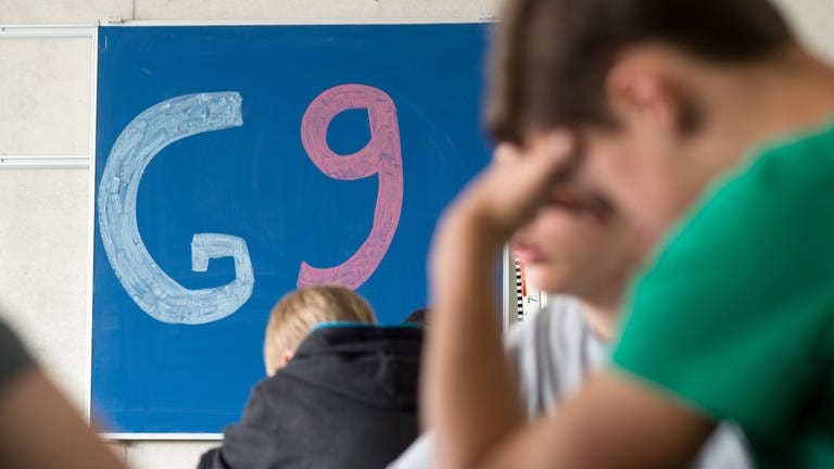 "G9" steht in einem Gymnasium an einer Tafel.