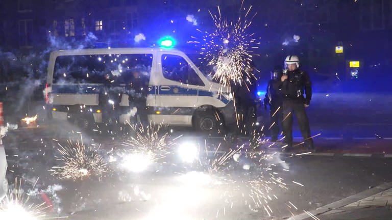 Polizeibeamte stehen hinter explodierendem Feuerwerk. (Foto: picture-alliance / Reportdienste, Picture Alliance)