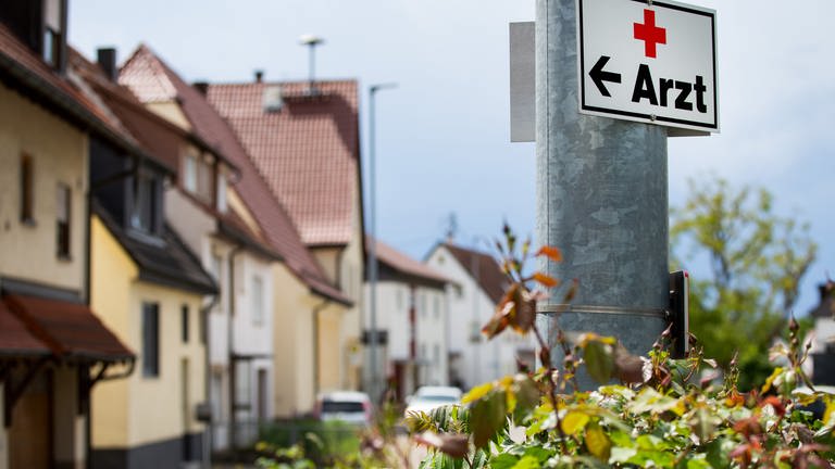 Ein Schild mit der Aufschrift "Arzt" hängt an einer Straßenlaterne: Diskussion um die Landarztquote in Baden-Württemberg.