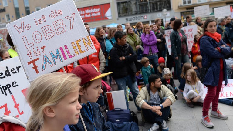 Ein Junge hält am 27.05.2015 während einer Kundgebung auf dem Marienplatz in München (Bayern) ein Plakat mit der Aufschrift «Wo ist die Lobby für Familien» in die Höhe. Beschäftigte kommunaler Kitas befinden sich seit drei Wochen im Streik. Eltern rufen zu weiteren Verhandlungen zwischen Erziehern und Kita-Betreibern im Kita-Streik auf.