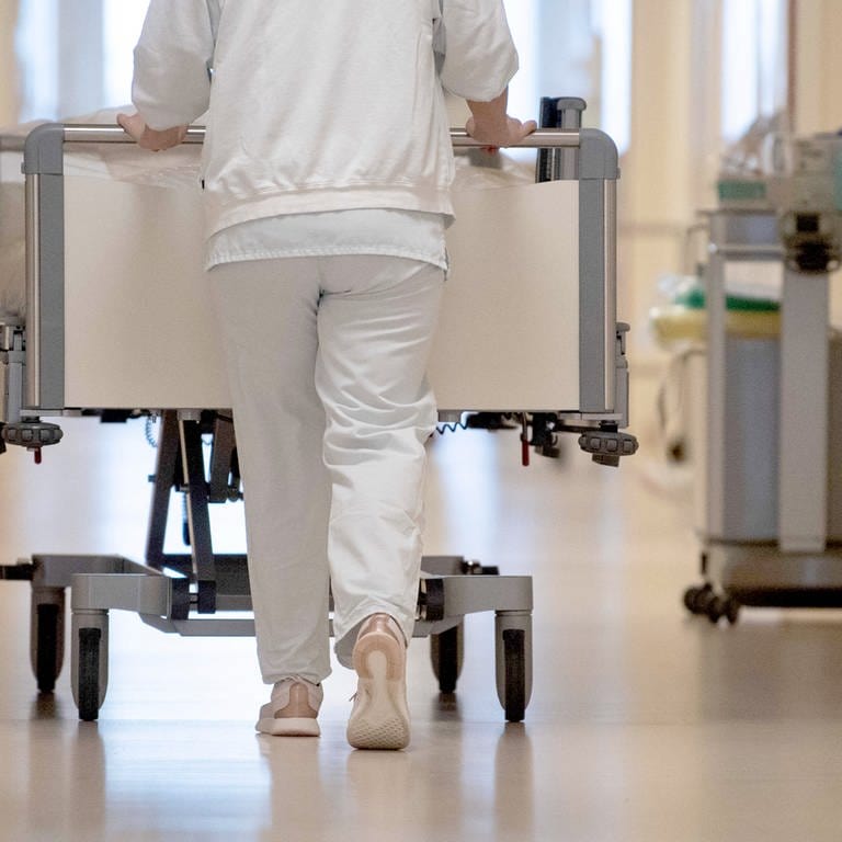 Eine Krankenpflegerin schiebt ein Krankenbett durch einen Flur