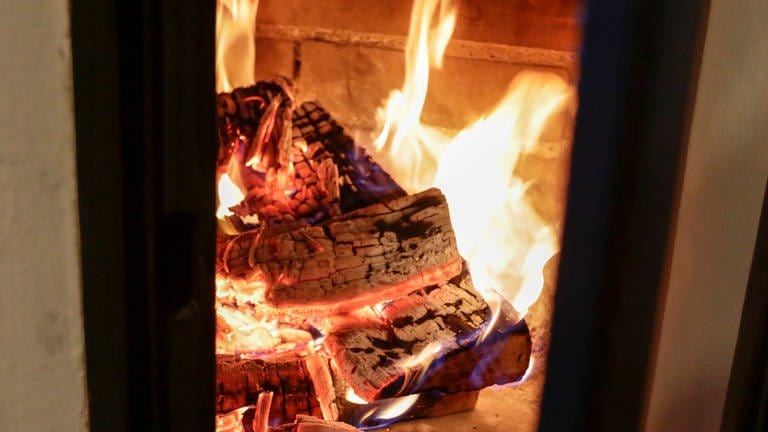 Brennendes Holz in einem Kachelofen (Foto: IMAGO, IMAGO / Roland Mühlanger)