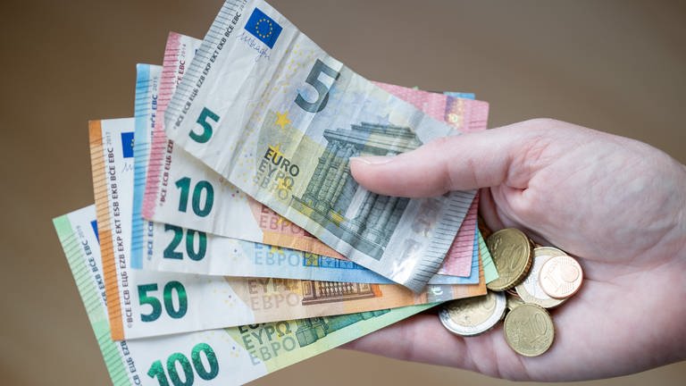 Eine Frau hält Geldscheine und Münzen in der Hand (Foto: picture-alliance / Reportdienste, picture alliance/dpa/Deutsche Presse-Agentur GmbH | Daniel Karmann)