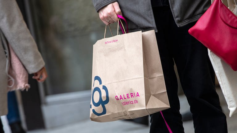 Ein Mann trägt eine Papiertasche mit dem Logo der Kaufhauskette Galeria Karstadt Kaufhof.