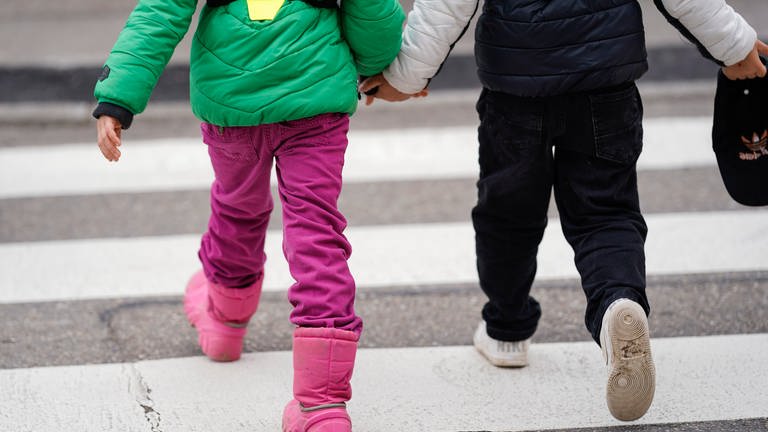 Kinder laufen Hand in Hand über die Straße