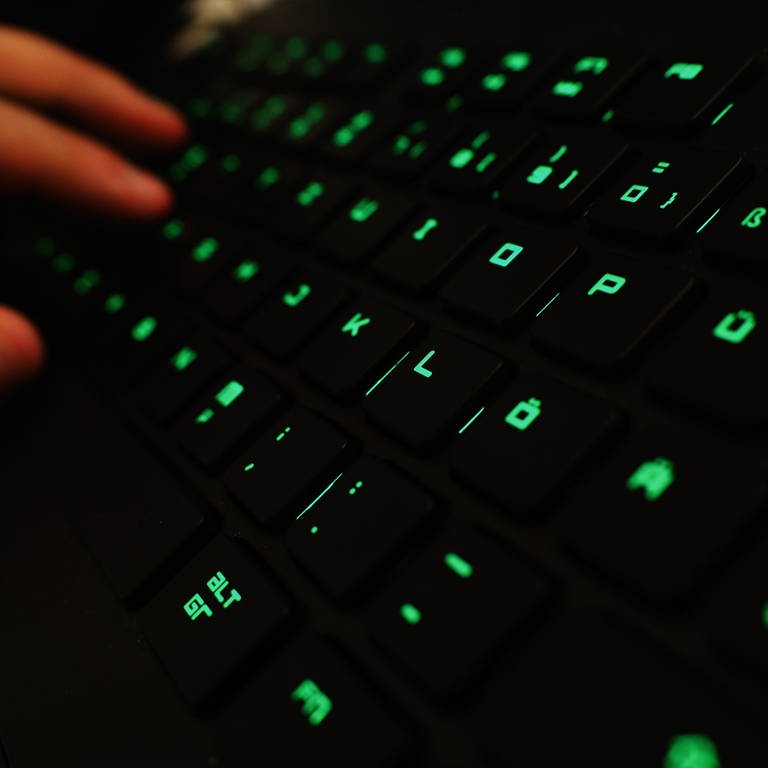 Ein Mann tippt auf einer beleuchteten Tastatur an einem Laptop. Symbolbild zu Hackerangriff auf IT-Dienstleister für Krankenkassen. (Foto: dpa Bildfunk, picture alliance/dpa | Nicolas Armer)