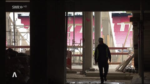 Ein Bauarbeiter läuft durch die Baustelle für die neue Haupttribühne der Mercedes-Benz-Arena.