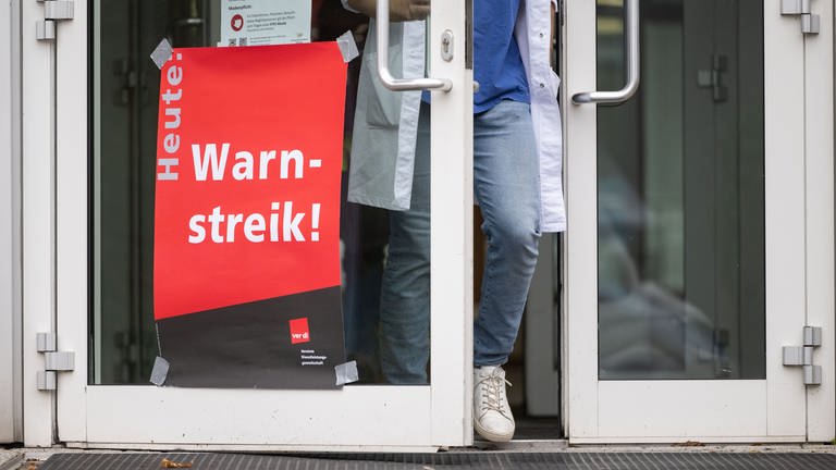 Ein Plakat mit der Aufschrift "Heute Warnstreik" hängt am Eingang eines Gebäudes des Universitätsklinikum Tübingen (Archivbild).  (Foto: dpa Bildfunk, picture alliance/dpa | Marijan Murat)