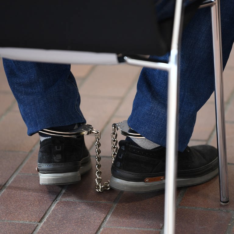 Ein Mafia-AngeklagteR sitzt mit Fußfesseln im Gerichtssaal auf seinem Stuhl.