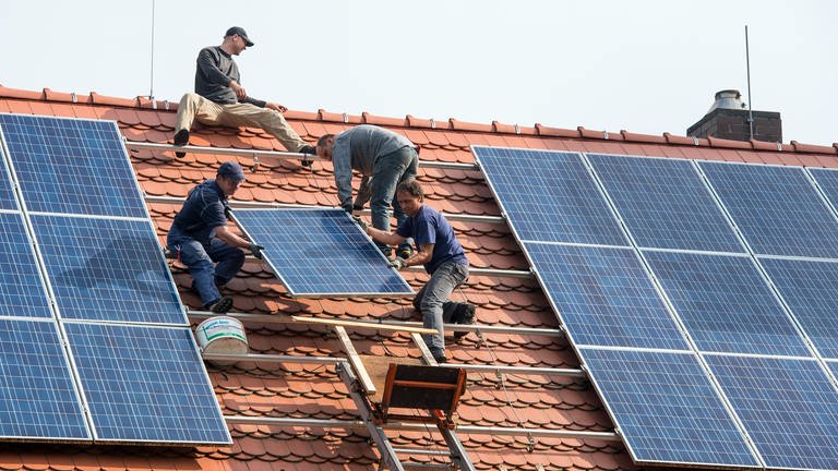 Auf einem Hausdach werden Solarmodule installiert. Landesregierung von BW will jetzt bei Regierungsgebäuden nachlegen.