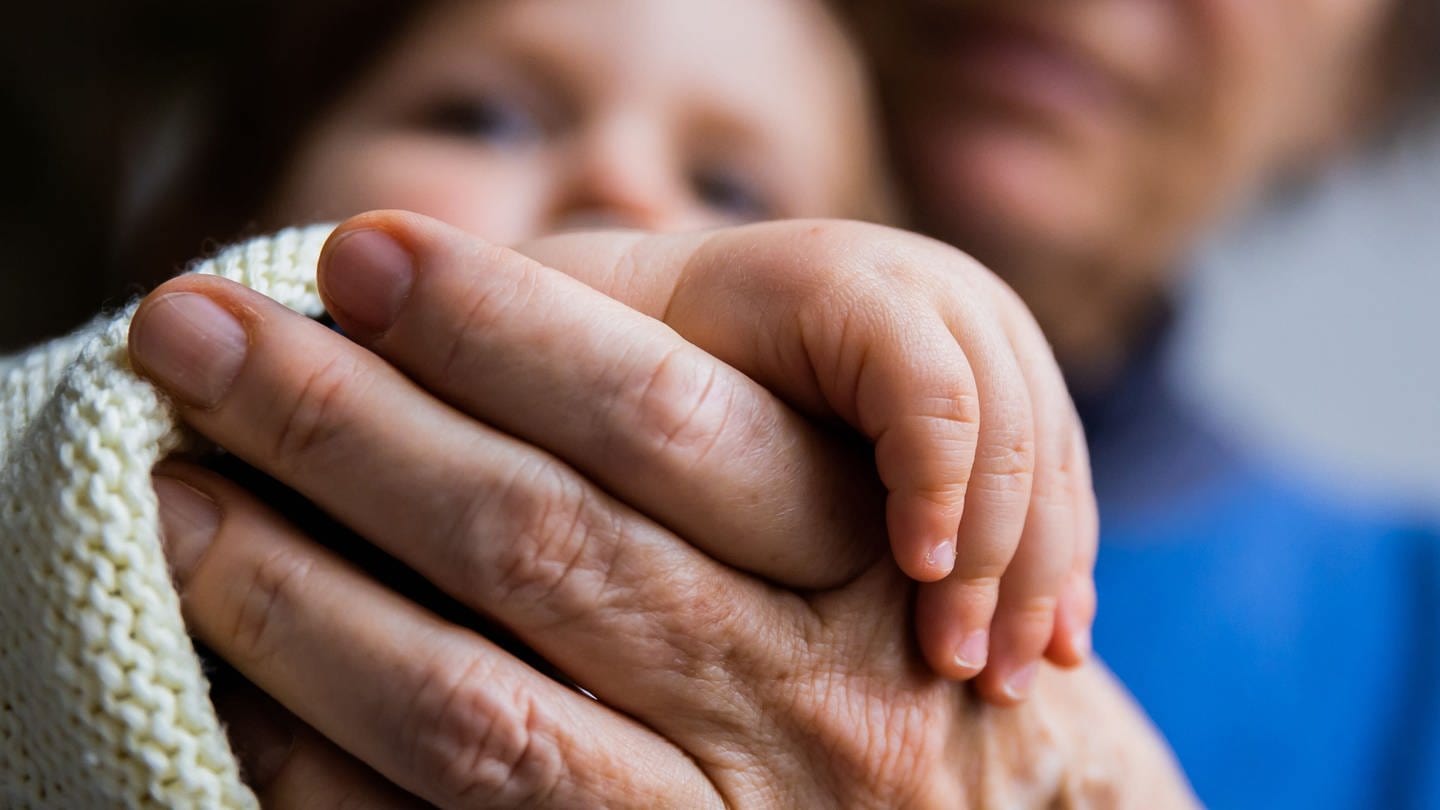 Die Hände von Enkel und Oma liegen ineinander. (Foto: dpa Bildfunk, picture alliance/dpa | Christoph Soeder)
