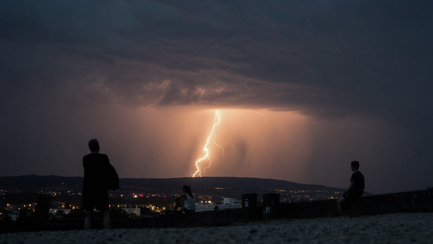 Menschen schauen sich auf einem Aussichtspunkt eine heraufziehende Gewitterfront an. (Foto: dpa Bildfunk, picture alliance/dpa | Sebastian Gollnow)