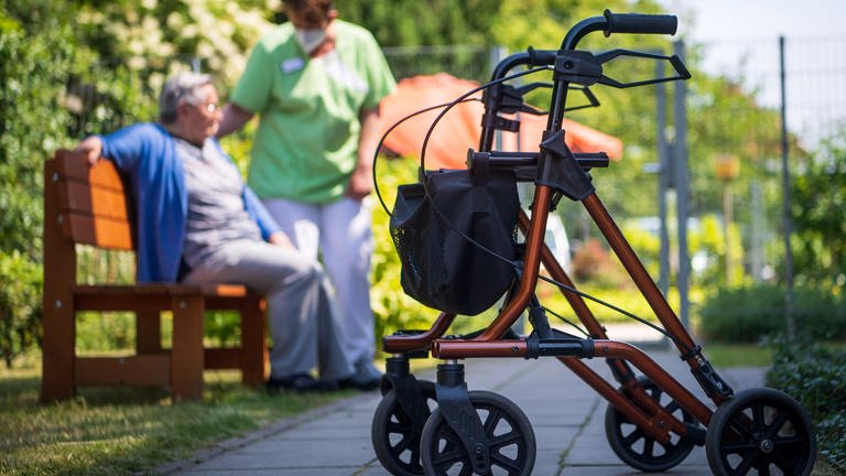 Ein Rollator steht nahe einer Pflegefachkraft und einer Bewohnerin des Seniorenheims 