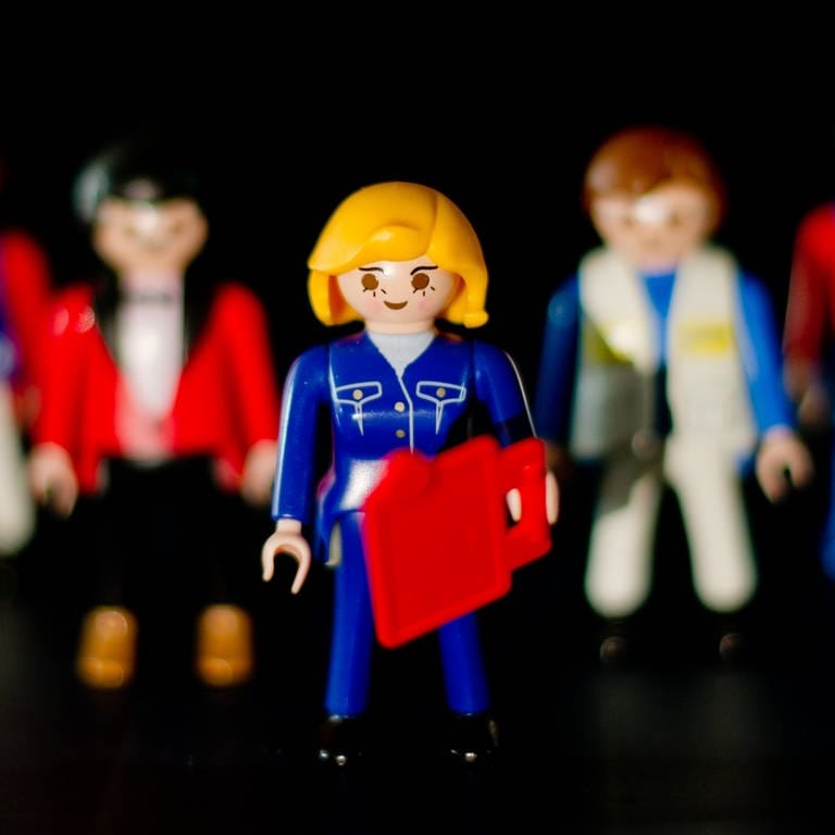 Eine weibliche Playmobil-Figur mit steht vor mehreren männlichen Figuren: Der Städtetag Baden-Württemberg will mehr Frauen für das Amt der Bürgermeisterin gewinnen. (Foto: dpa Bildfunk, Picture Alliance)